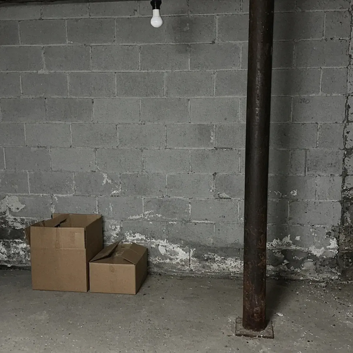 Basement block wall with a water stain and white chalky residue near the floor